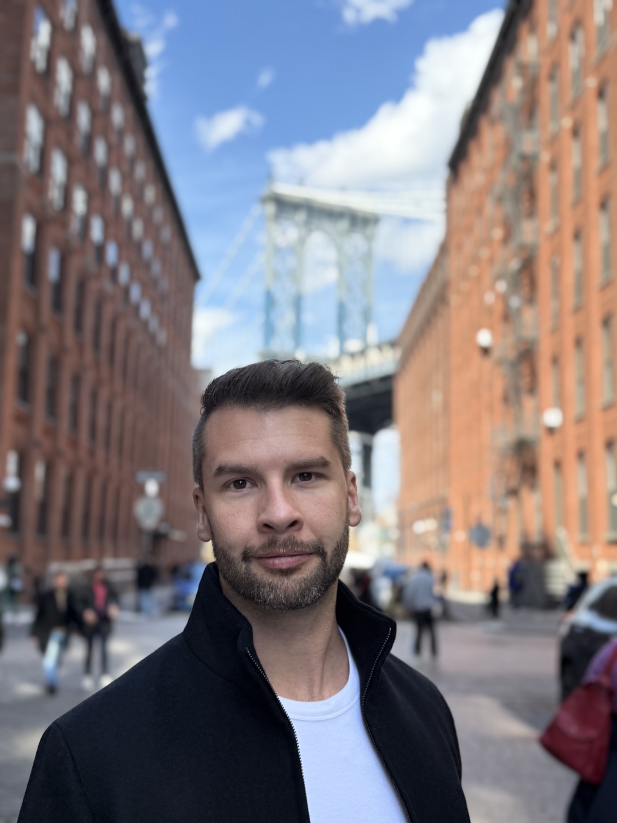 Stefan Friend in DUMBO, Brooklyn with the Manhattan Bridge behind him